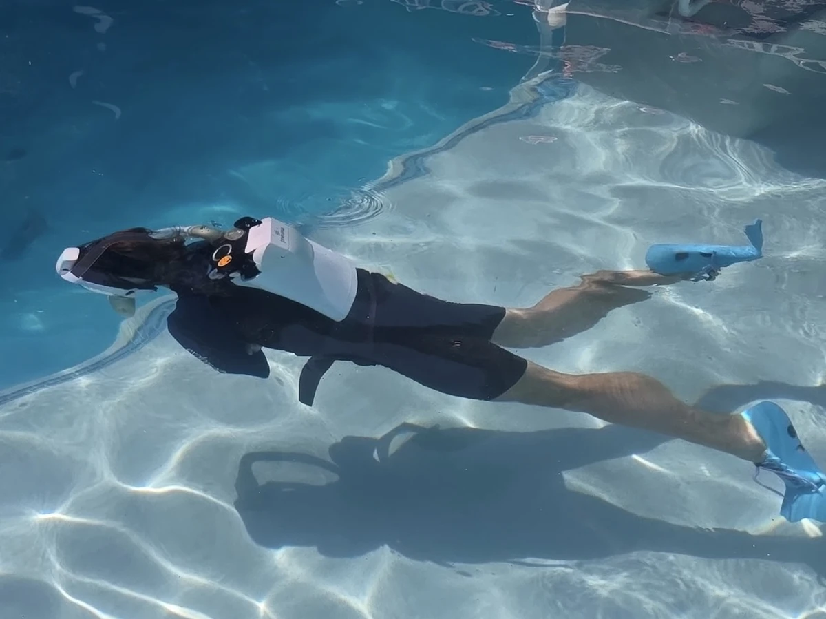 Two divers in a test pool wearing Pneuma units, the status ring lit on the mask